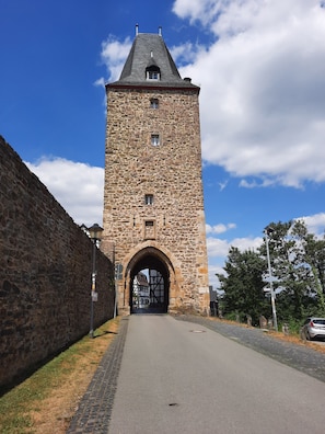 A stone tower with a large arched entrance, a paved pathway, and a clear sky.