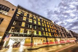 Un hotel de varios pisos con fachada moderna, una entrada destacada y una bandera.