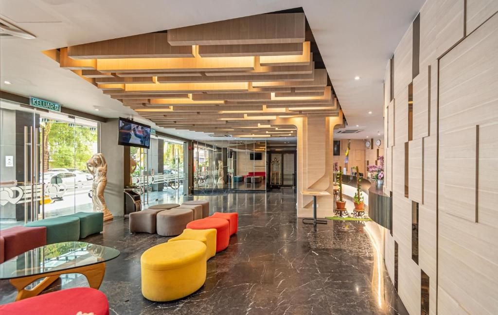 A modern lobby with a glass storefront, seating areas, and a television screen.