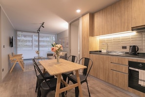 A modern kitchen with wooden cabinets, a black countertop, and a built-in oven. - Pedro Valdivia Apts. By Andes STR (Providencia)