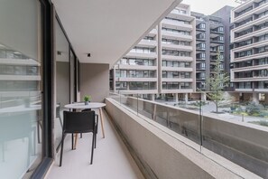 A balcony with a table and chairs, overlooking a residential building with multiple balconies. - Pedro Valdivia Apts. By Andes STR (Providencia)