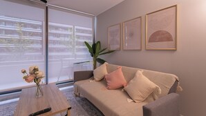 Un salón con un sofá, una mesa de centro y una planta. Hay obras de arte enmarcadas en la pared.