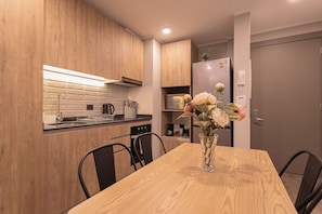 Una cocina moderna con armarios de madera, una mesa de comedor, sillas, una cafetera y un refrigerador.