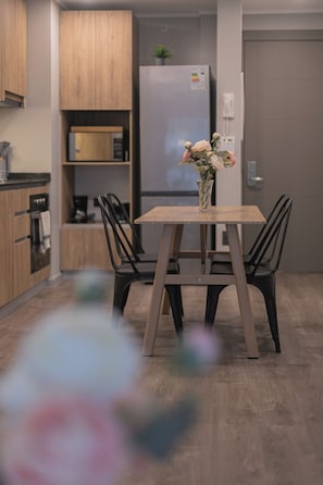 Eine moderne Küche mit Holzausstattung, einem integrierten Kühlschrank und einem Esstisch mit Stühlen.