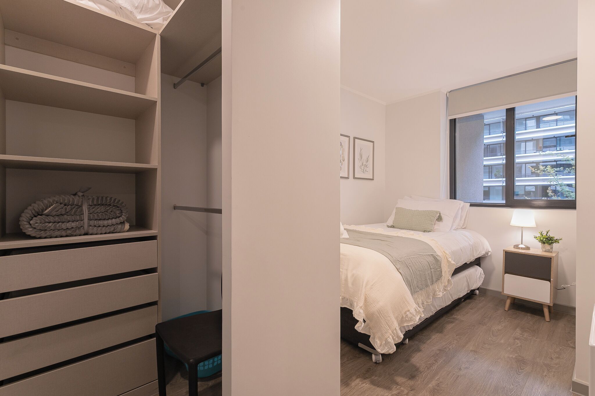 A bedroom with a bed, bedside table, lamp, and window.