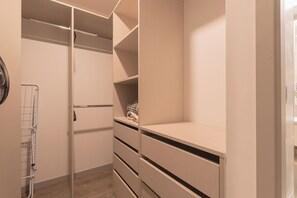 Ein begehbarer Kleiderschrank mit offenen Regalen, einer Kleiderstange und einem gefalteten Handtuch auf der untersten Ablage.