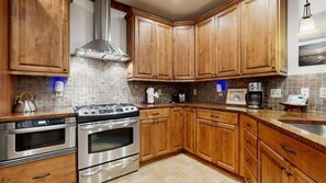A kitchen with wooden cabinets, stainless steel appliances, and a tiled backsplash. - Luxury Lakefront Condo, Gated Community, Mountain & Lake Views, Pool, Dock, & Kayaks (Lake Lure)