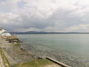 Eine Küstenlandschaft mit einem weißen Gebäude, einem Steg und ruhigem Wasser.