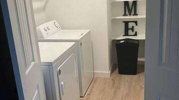 A laundry room with a washing machine, dryer, and a shelf with detergent.