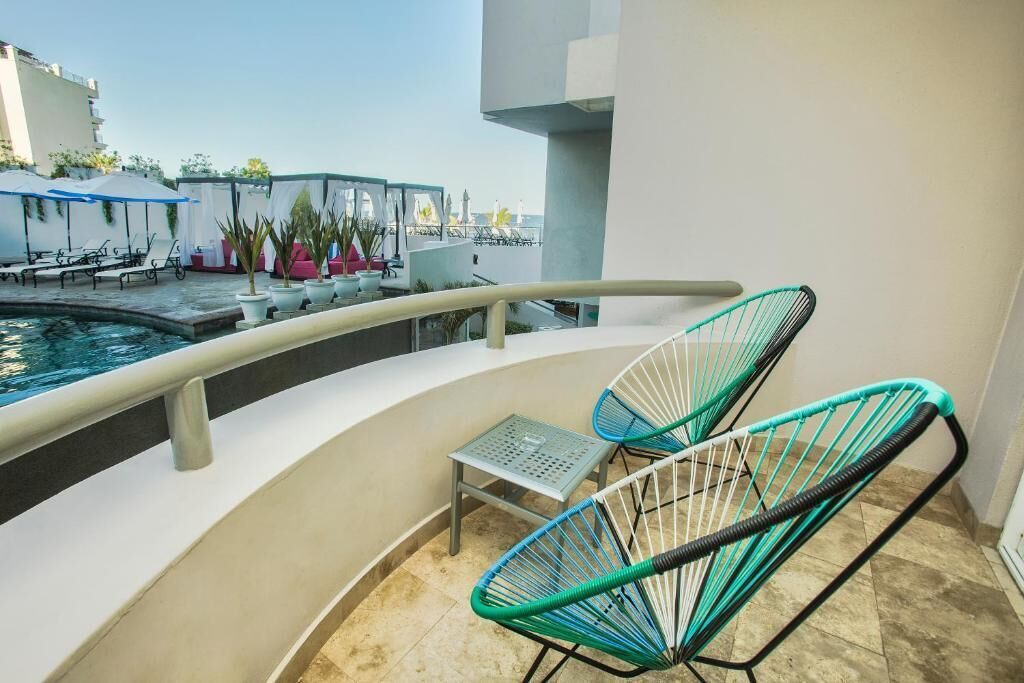 Un área junto a la piscina con sillas de descanso, una mesita y una piscina.