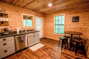 Uma cozinha no estilo cabana com paredes de madeira, uma pia e um espaço de refeições com banquetas.