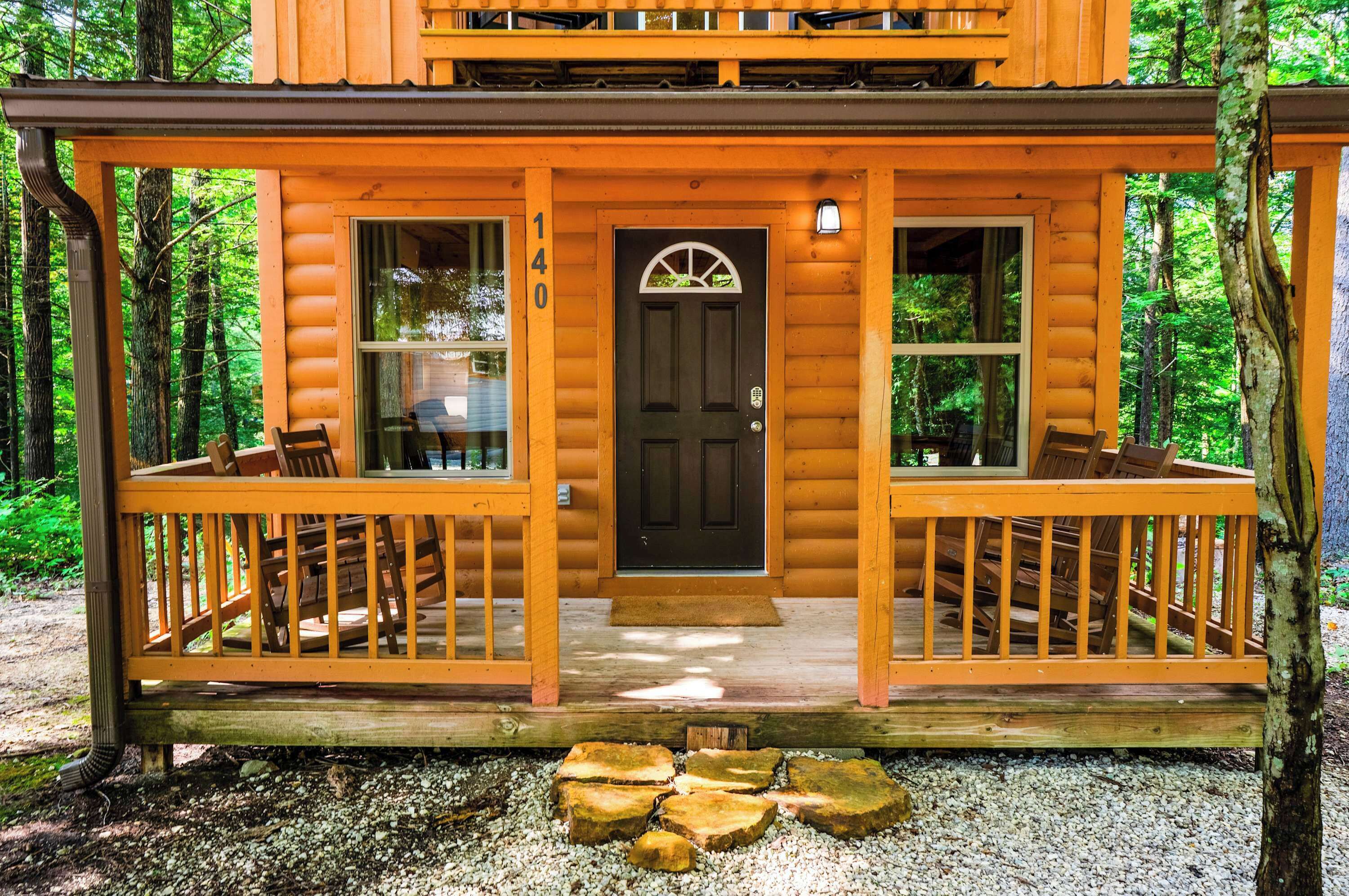 A log cabin with a front porch, two windows, and a door.