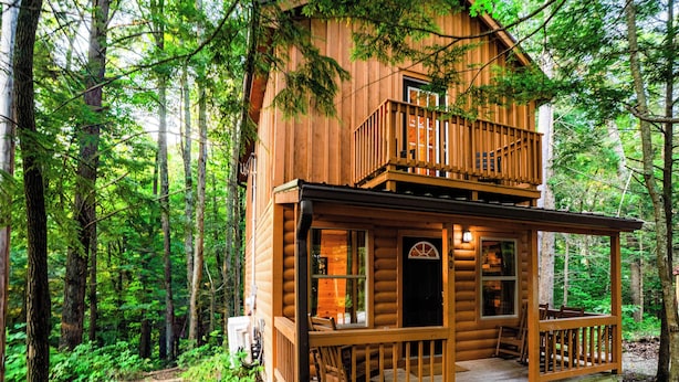 A two-story log cabin with a balcony, surrounded by a forest. - Buttercup - Cozy Retreat - Central - WiFi (Gillmore)
