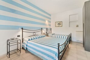 A bedroom with a bed, bedside tables, a radiator, and a striped wall. - [StairwayToHeaven Room 1] 5Terre-Seaview (Riomaggiore)
