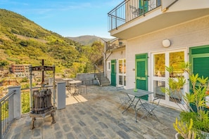 A terrace with outdoor furniture, a vintage water pump, and a view of a hillside. - [StairwayToHeaven Room 1] 5Terre-Seaview (Riomaggiore)