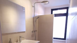 A modern bathroom with a shower, a sink, and a mirror.
