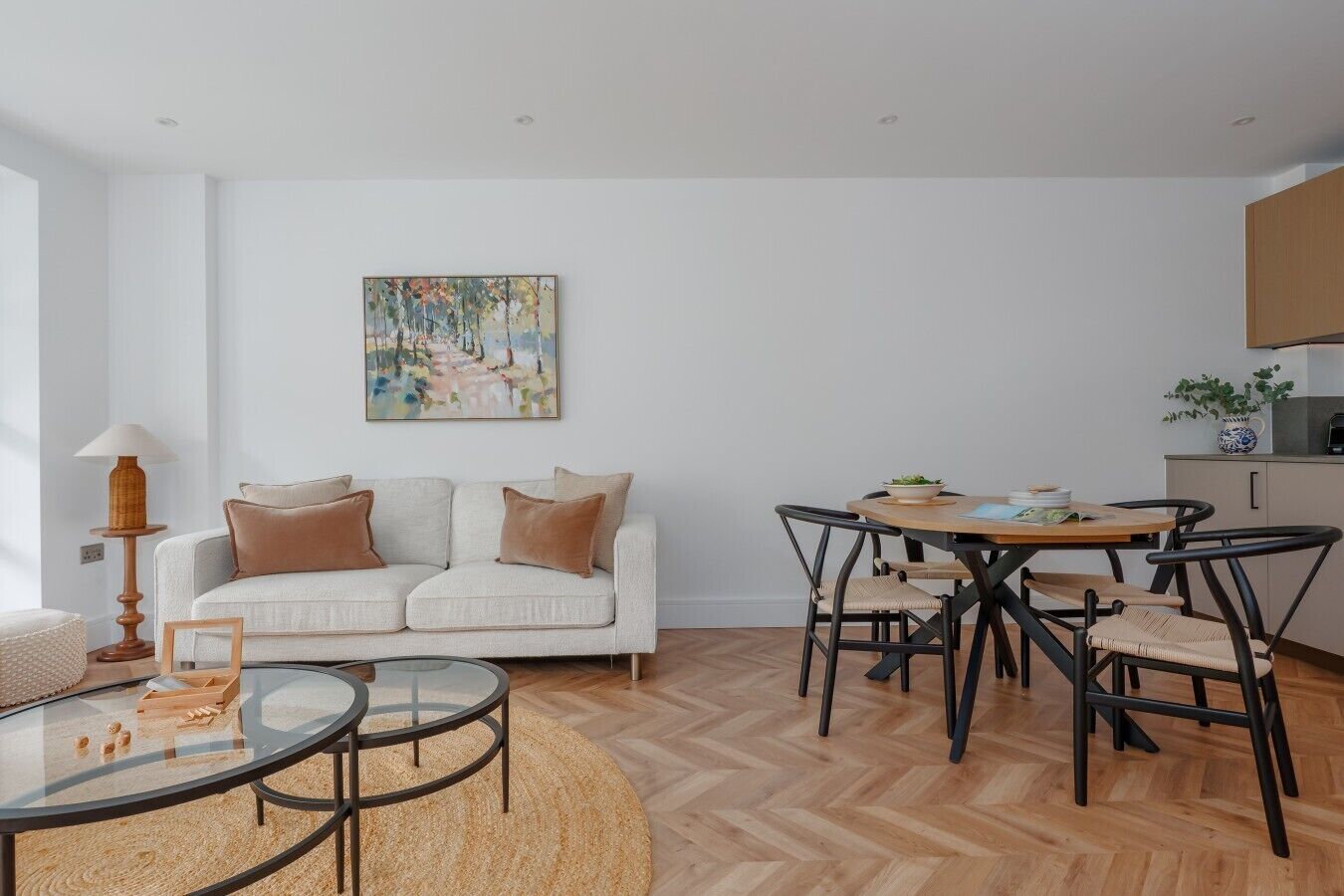 A modern living room with a sofa, a glass coffee table, and a dining area with chairs and a table.