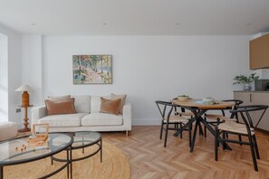 Una sala de estar moderna con un sofá, una mesa de centro de vidrio y una zona de comedor con sillas y una mesa.