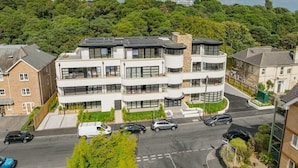 Um edifício residencial de vários andares com design arquitetônico moderno, com varandas e janelas amplas.