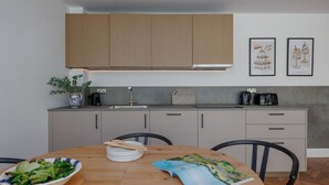 Uma cozinha moderna com armários cinzas, uma mesa de jantar de madeira e uma revista.