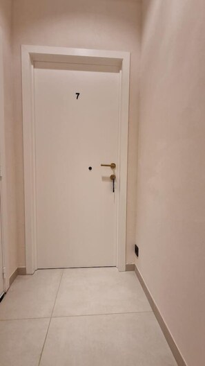 Una puerta blanca con el número 7, un agujero para la llave y una llave pequeña insertada.