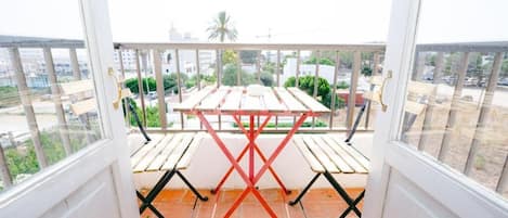 Un balcón con mesa y sillas, con vistas a un paisaje urbano.