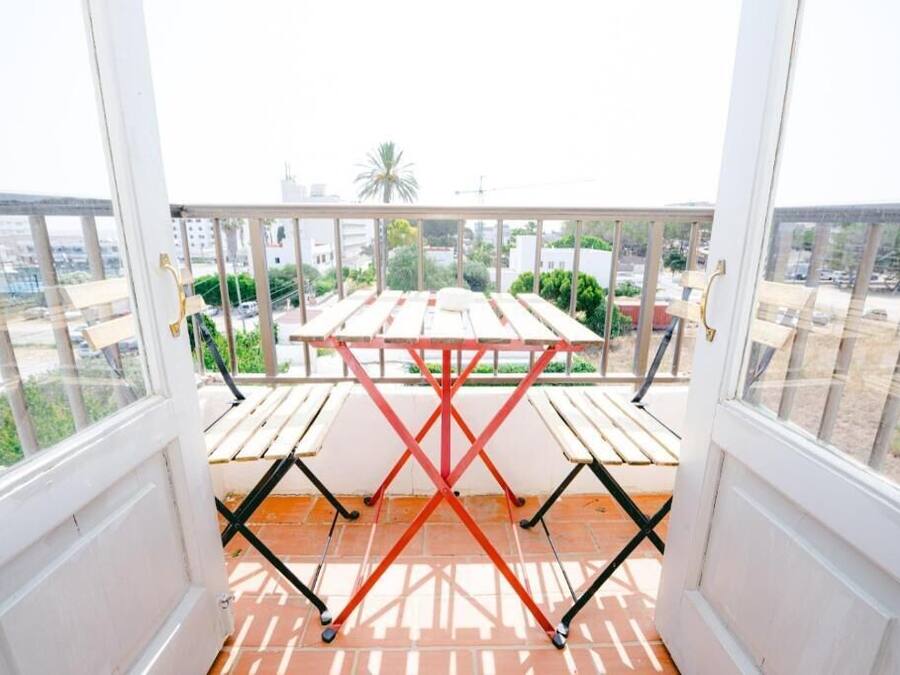 A balcony with a table and chairs, overlooking a cityscape.