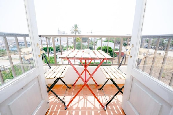 A balcony with a table and chairs, overlooking a cityscape. - Flamingo by Nest (Santa Eulalia del Rio)