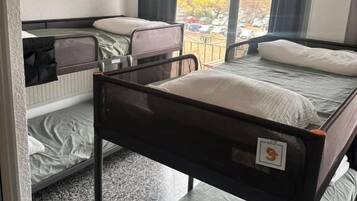Habitación de hotel con literas, ventana con cortinas y un equipo de aire acondicionado.