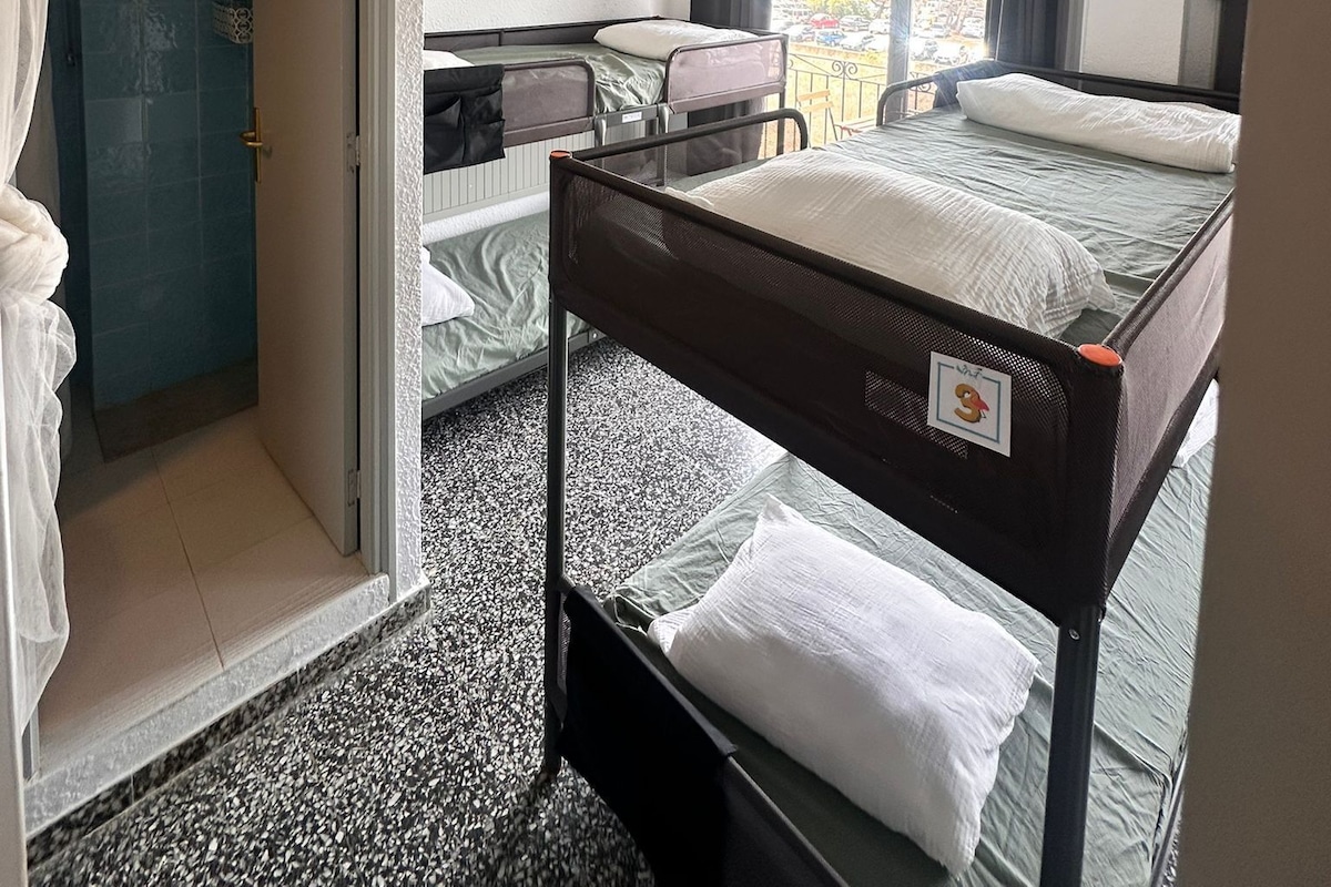 Habitación de hotel con literas, un escritorio y vistas al exterior.