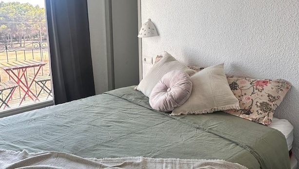 Une chambre d’hôtel avec un lit, une fenêtre avec des rideaux, un appareil de climatisation et une vue sur l’extérieur.