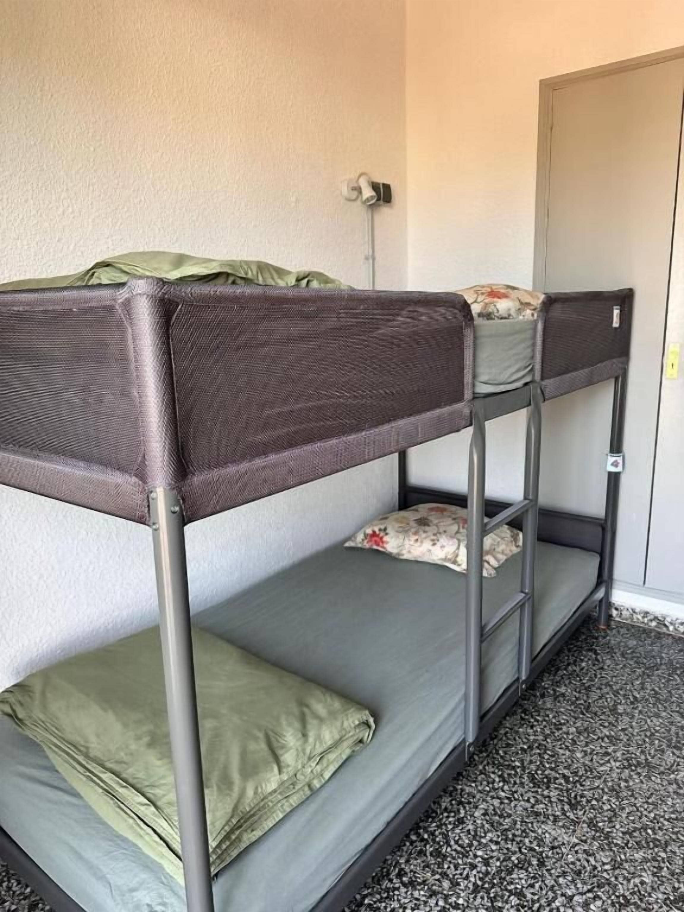 A bunk bed with a metal frame, a green pillow, and a floral pillow on the top bunk.