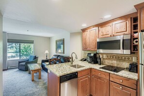 A compact kitchen with wooden cabinets, a stainless steel microwave, and a dishwasher. - 2 Studios Steps to Lift | Pool, Hot Tubs & Slopes (Breckenridge)