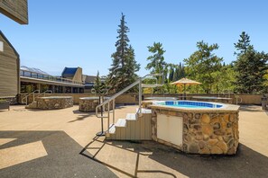 An outdoor swimming pool area with a stone wall, a hot tub, and a staircase leading to a covered deck. - 2 Studios Steps to Lift, Pool, Hot Tubs & Slopes (Breckenridge)