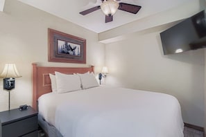 A hotel room with a bed, a ceiling fan, a TV mounted on the wall, and a framed picture above the bed. - 2 Studios Steps to Lift, Pool, Hot Tubs & Slopes (Breckenridge)