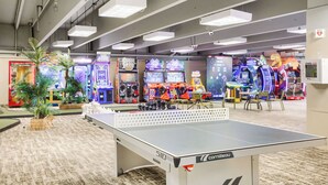 Een speelhal met diverse machines, een tafeltennistafel en een zichtbare AED-noodstation.
