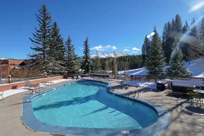 A swimming pool with a view of snow-covered trees and a mountain in the background. - 2 Studios Steps to Lift | Pool, Hot Tubs & Slopes (Breckenridge)