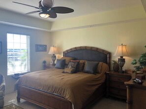 A bedroom with a bed, two bedside tables with lamps, a ceiling fan, and a window with blinds. - Spacious 3-bedroom condo in lovely Naples with fitness room (Naples)