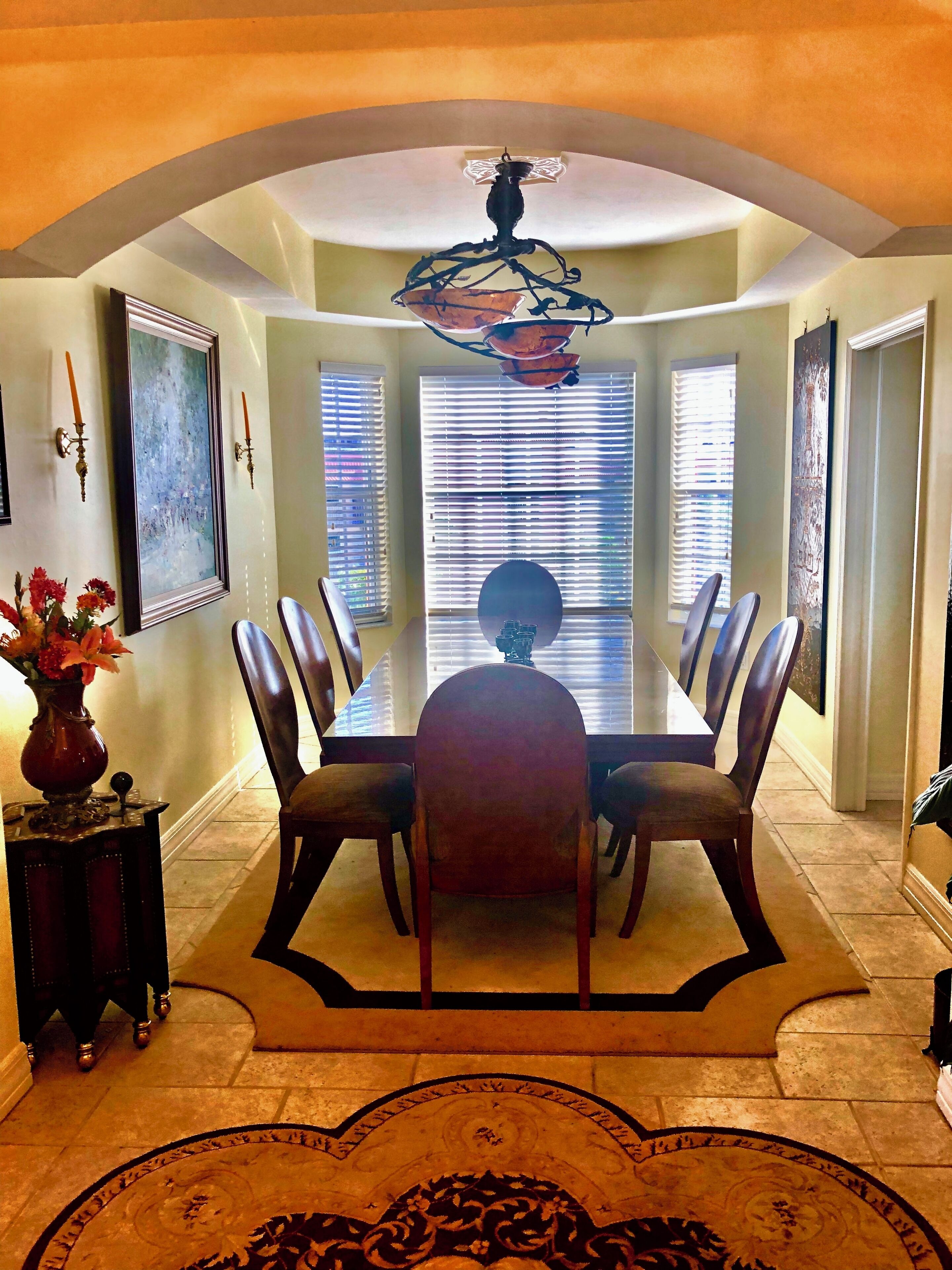 Un coin repas comprenant une table, des chaises, un vase avec des fleurs et un tapis à motifs.