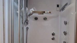 A walk-in shower with a glass door, a handheld showerhead, a wall-mounted faucet, and a shelf. - ROOM N°6 / Deluxe Room in Historic City Centre • Private External Bathroom (Bruges)