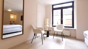 A hotel room with a bed, a large mirror, two white chairs, a small table, and a window with a view. - ROOM N°6 / Deluxe Room in Historic City Centre • Private External Bathroom (Bruges)