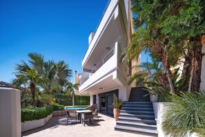 Un edificio moderno de varios pisos con piscina, asientos al aire libre y una escalera que conduce a la entrada.