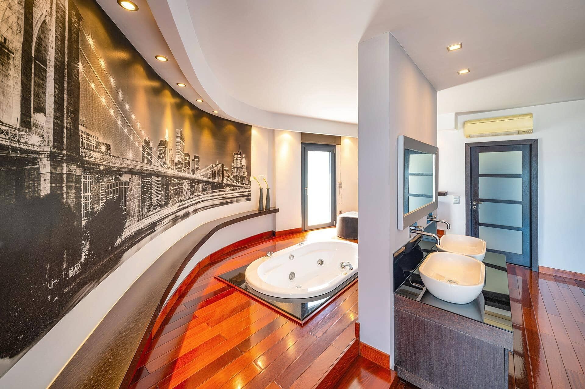 Un baño moderno con una bañera grande, un espejo y un mural con vistas a la ciudad.
