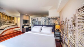 Ein Hotelzimmer mit einem großen Bett, einem Stadtbild-Wandgemälde, einem Schminktisch mit zwei Waschbecken und einem Nachttisch mit Lampe.