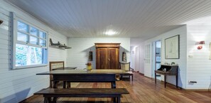 A room with a large wooden table, a bench, a wooden door, and a window with a view of trees. - Casa em Petropolis com Piscina e Vista da Montanha (Petrópolis)