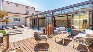 Eine moderne Außenpatio mit Lounge-Möbeln, einer Holzterrasse und einem eingezäunten Poolbereich mit Glas.