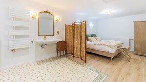 Ein Schlafzimmer mit einem Bett, einem Nachttisch, einem Spiegel, einem Heizkörper und einem Kleiderschrank.