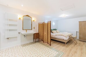 Un dormitorio con cama, mesita de noche, espejo, radiador y armario.