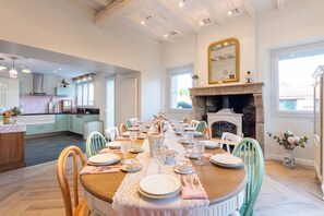 A dining area with a long wooden table set for a meal, surrounded by chairs. - Vrbo Property (Montaigu-Vendée)