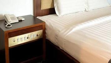 Une chambre d’hôtel avec une tête de lit en bois, un téléphone sur la table de chevet et un tapis à motifs.